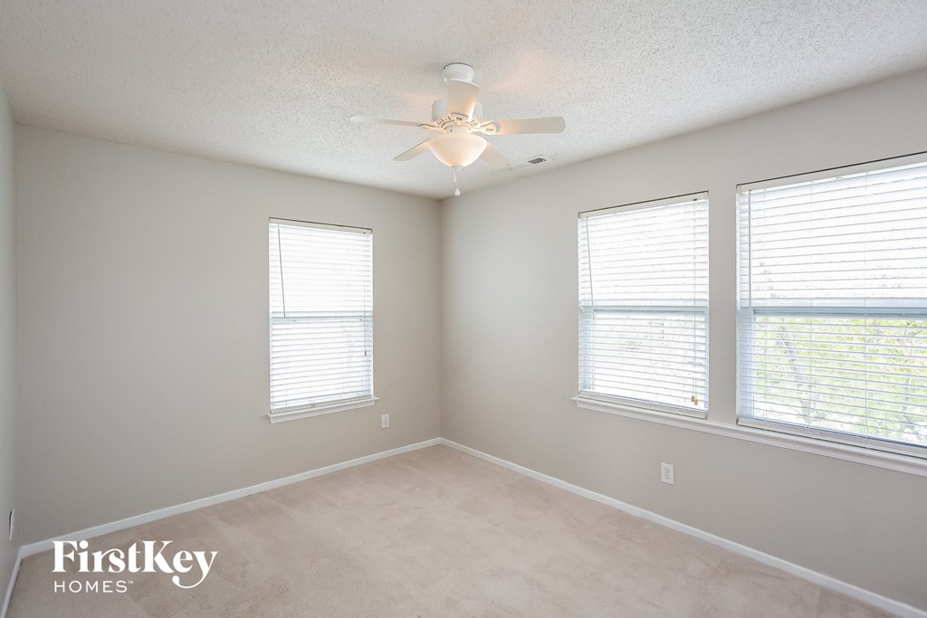 a bedroom with a ceiling fan and three windows