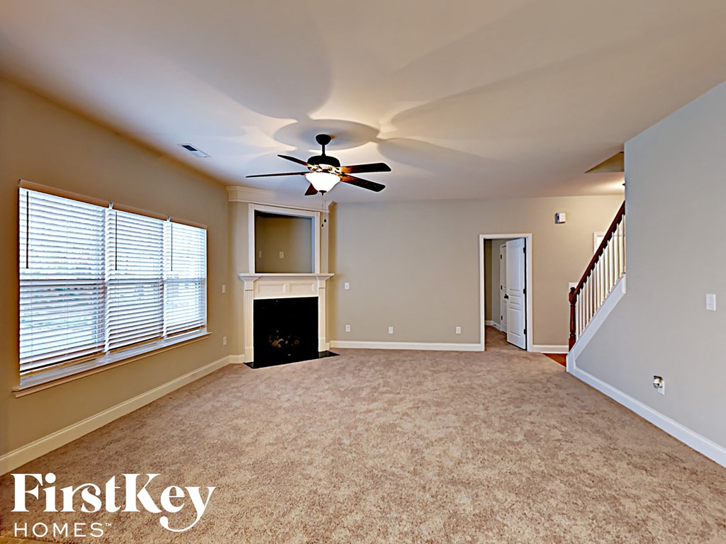 A spacious living room with a fireplace and a ceiling fan.