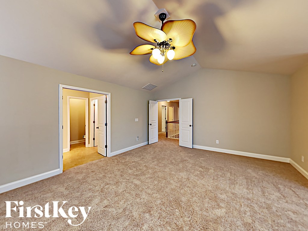 A spacious room with a carpeted floor and a ceiling fan with a light fixture.