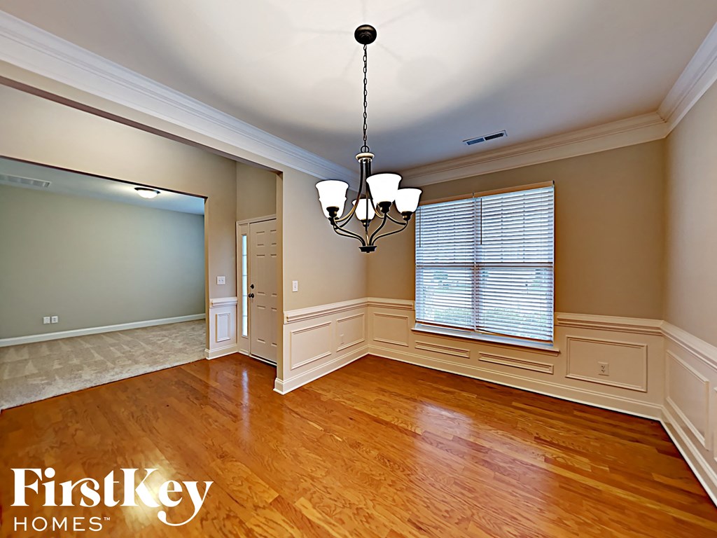 A well-lit room with wooden floors and a chandelier hanging from the ceiling.