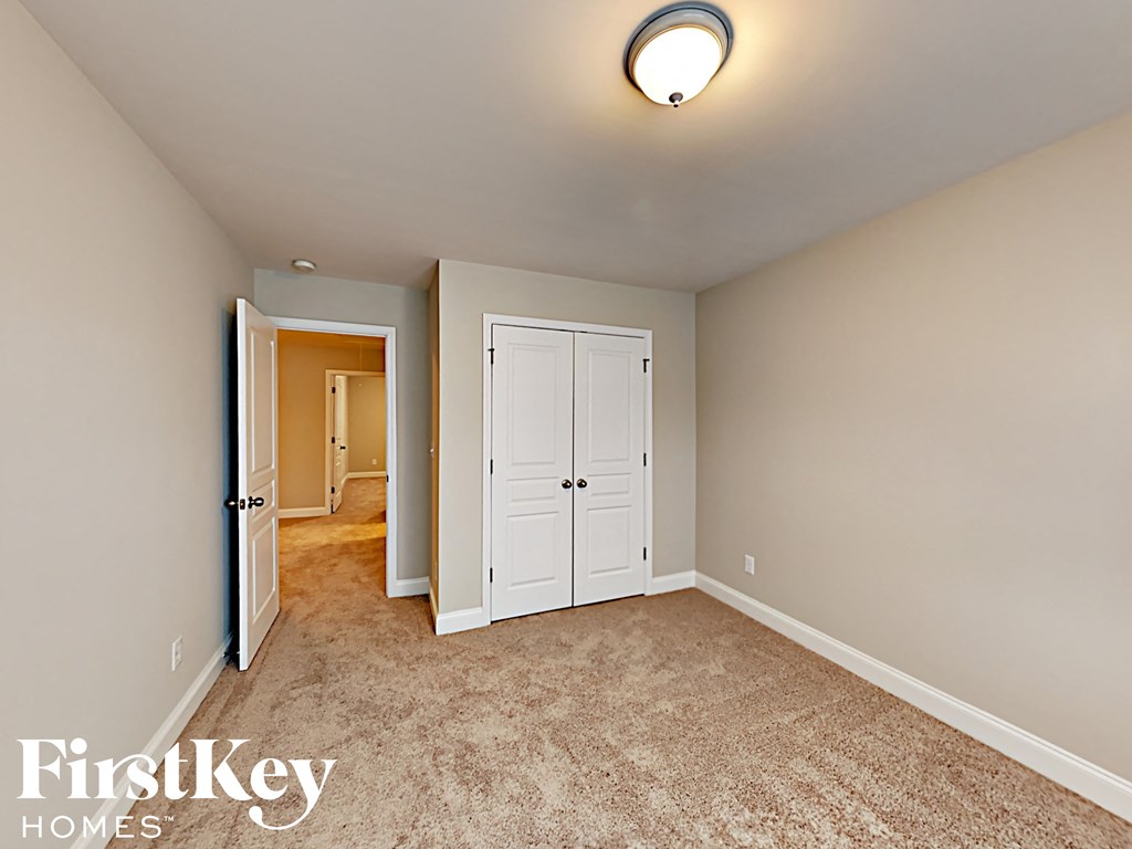 A bedroom with a carpeted floor and a white door.