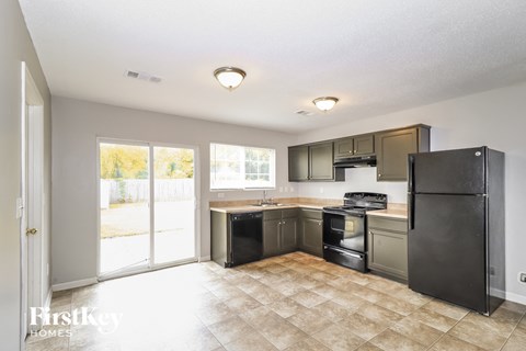A kitchen with tile flooring and a black refrigerator.