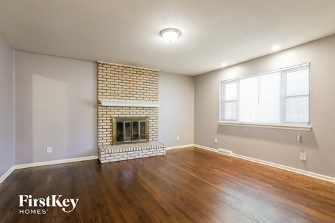 the living room has a brick fireplace and hardwood floors