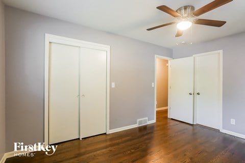 a bedroom with three closet doors and a ceiling fan