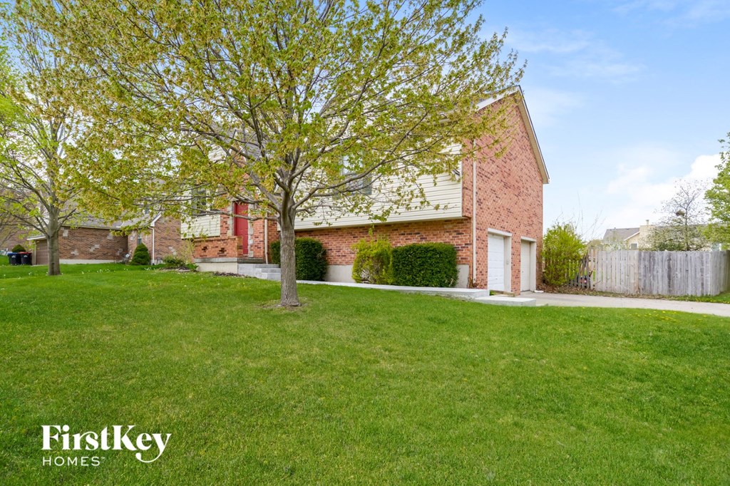 a home with a lawn and a tree in front of it
