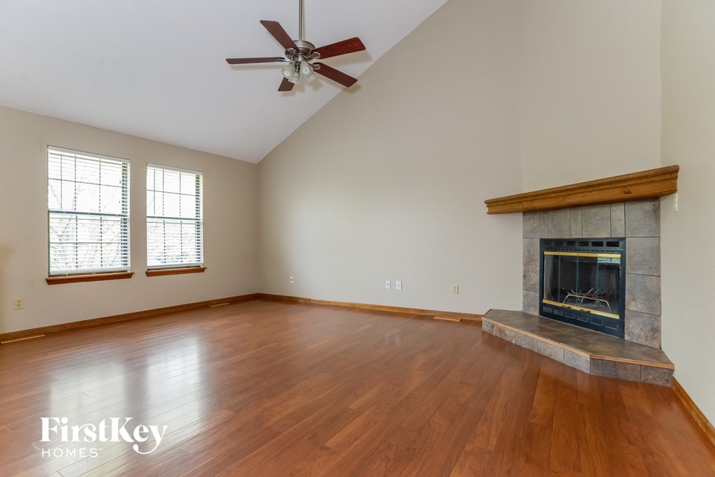 an empty living room with a fireplace and wooden floors