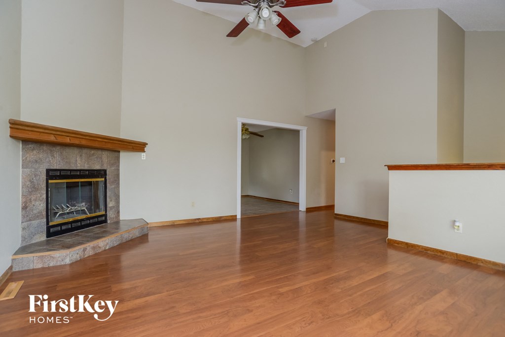 an empty living room with a fireplace and wooden floors