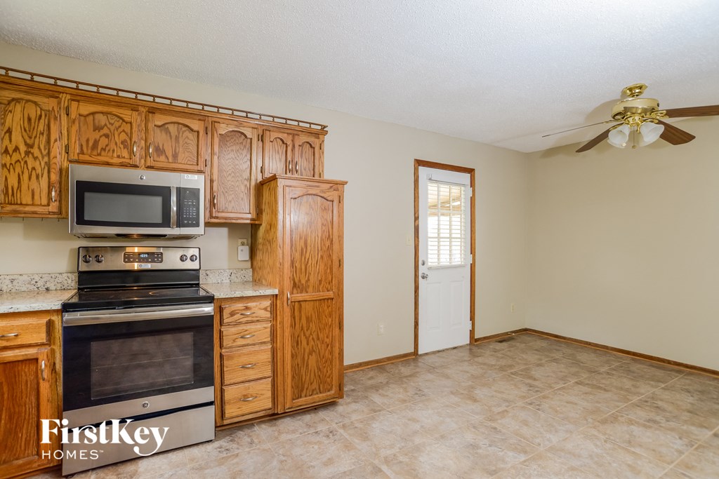 a kitchen with wooden cabinets and a stove and a ceiling fan