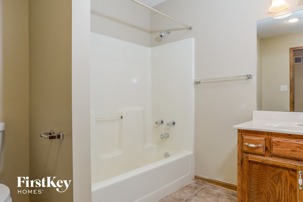a bathroom with a white tub and a sink and a mirror