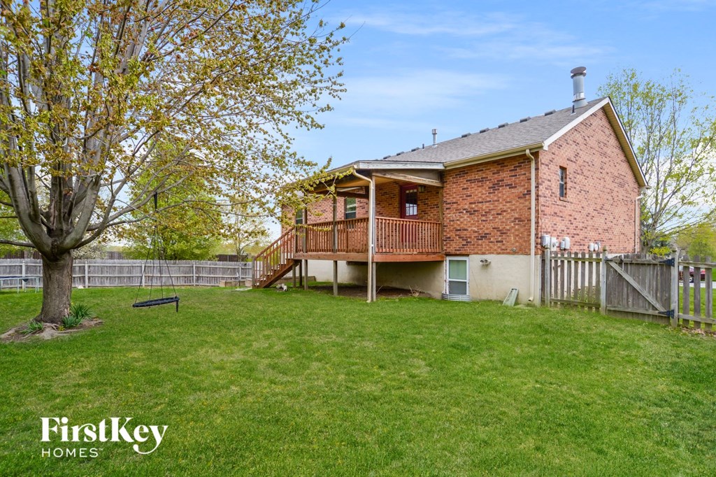 a backyard with a house with a deck and a tree