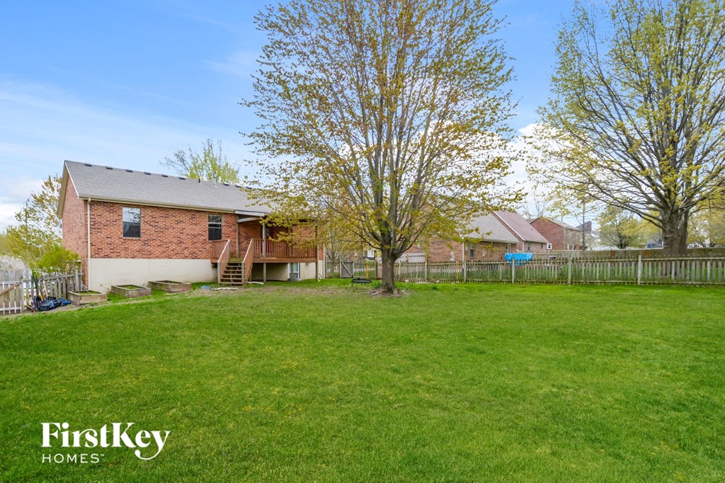 the backyard of a brick house with a yard and a fence