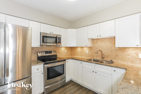 A kitchen with white cabinets and a stainless steel refrigerator.