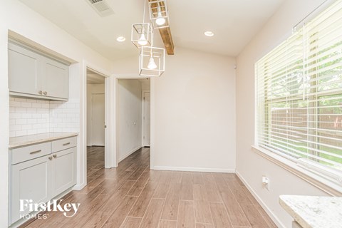a kitchen with white cabinets and wood floors and a large window