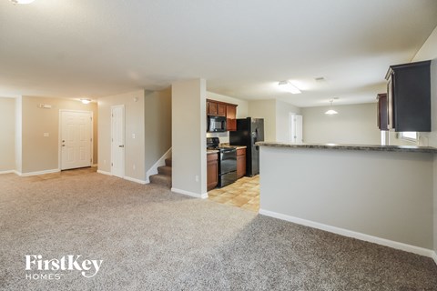 a kitchen and living room with a granite counter top and a black refrigerator and microwave