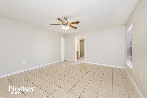 a spacious living room with tile flooring and a ceiling fan