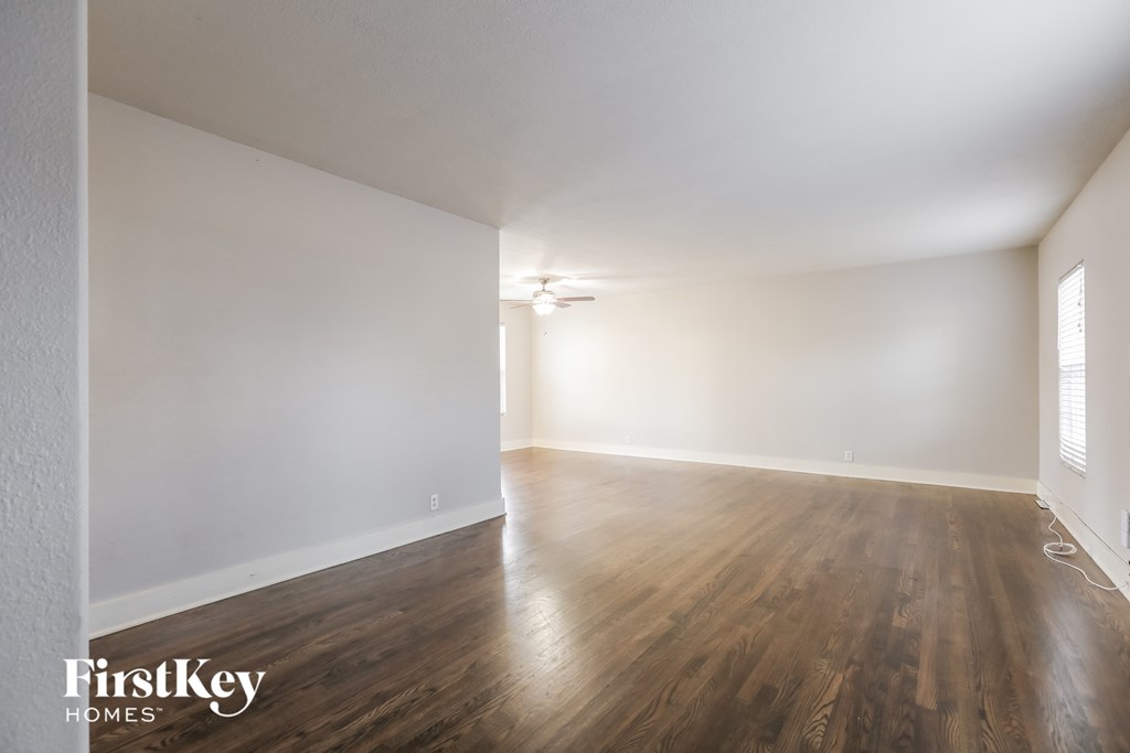 an empty living room with white walls and wood floors