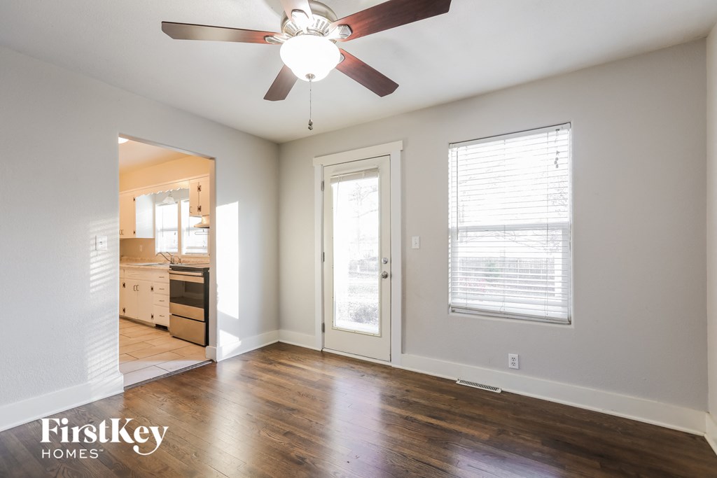 an empty living room with wood floors and a ceiling fan