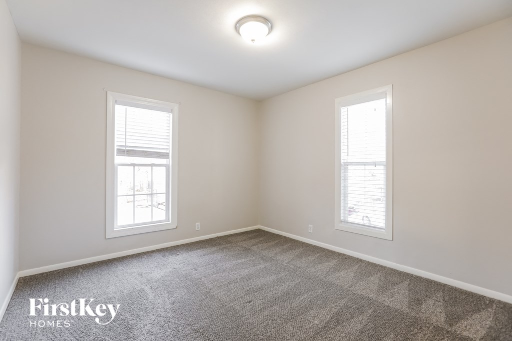a bedroom with two windows and a carpeted floor