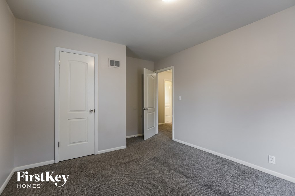 a bedroom with white doors and carpet and a door to a hallway