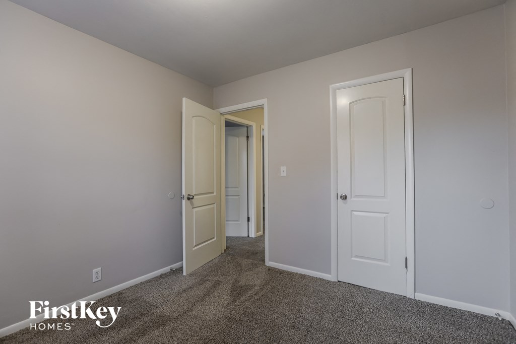 a bedroom with two doors and a hallway to two closets
