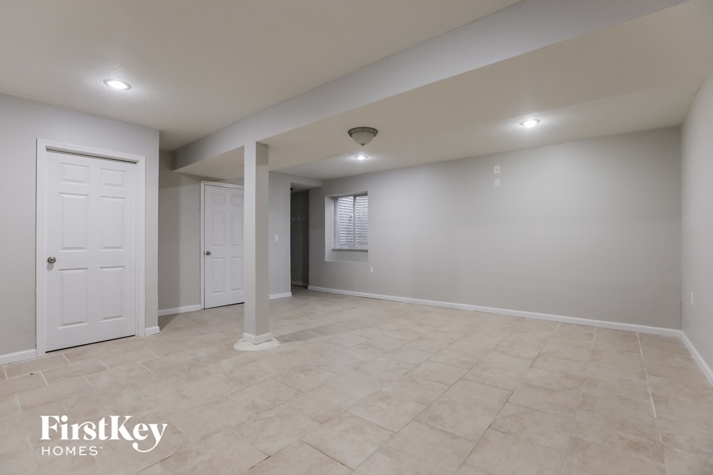 a empty living room with a white door and a tile floor