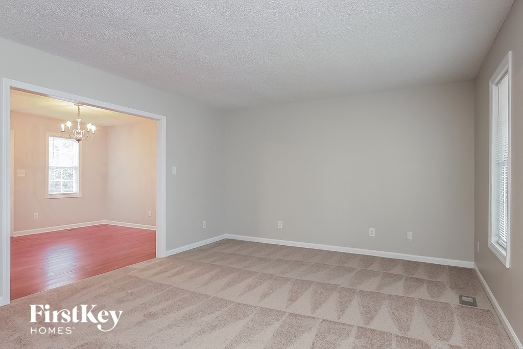 a living room with a carpeted floor and a door to a dining room
