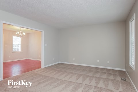 a living room with a carpeted floor and a door to a dining room