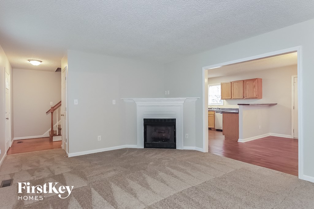a living room with a fireplace and a kitchen