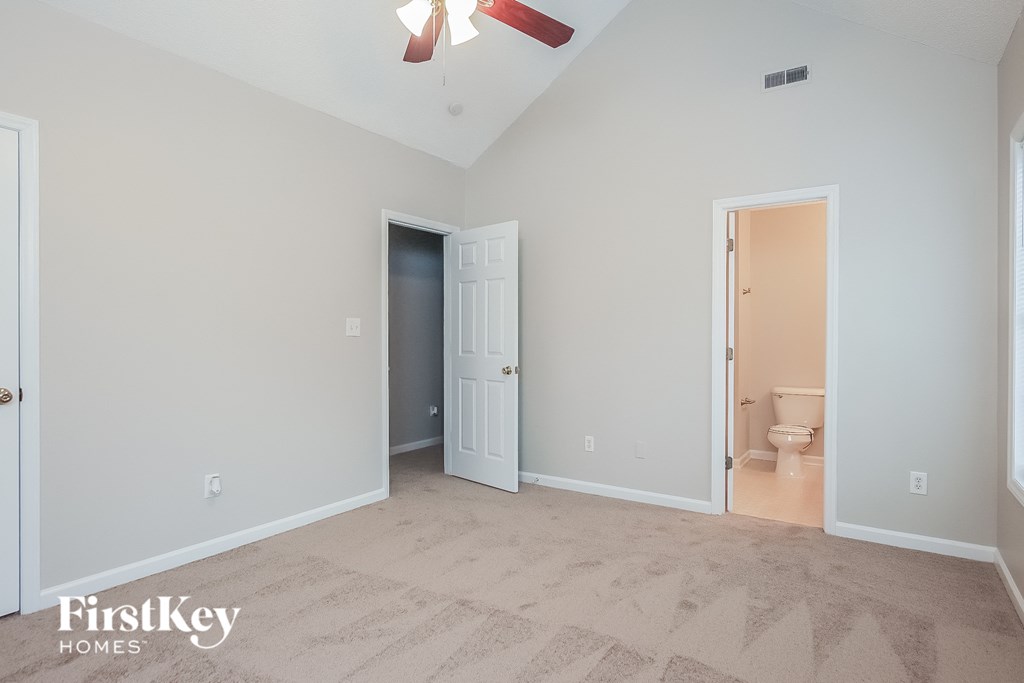 a bedroom with a door to a bathroom and a ceiling fan
