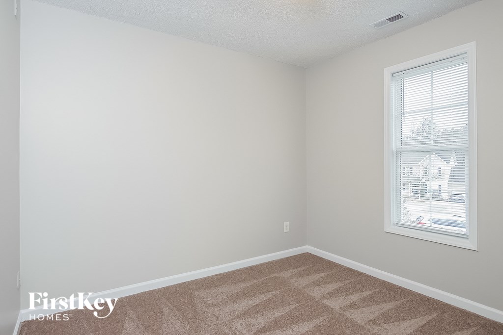 a bedroom with a window and a carpeted floor
