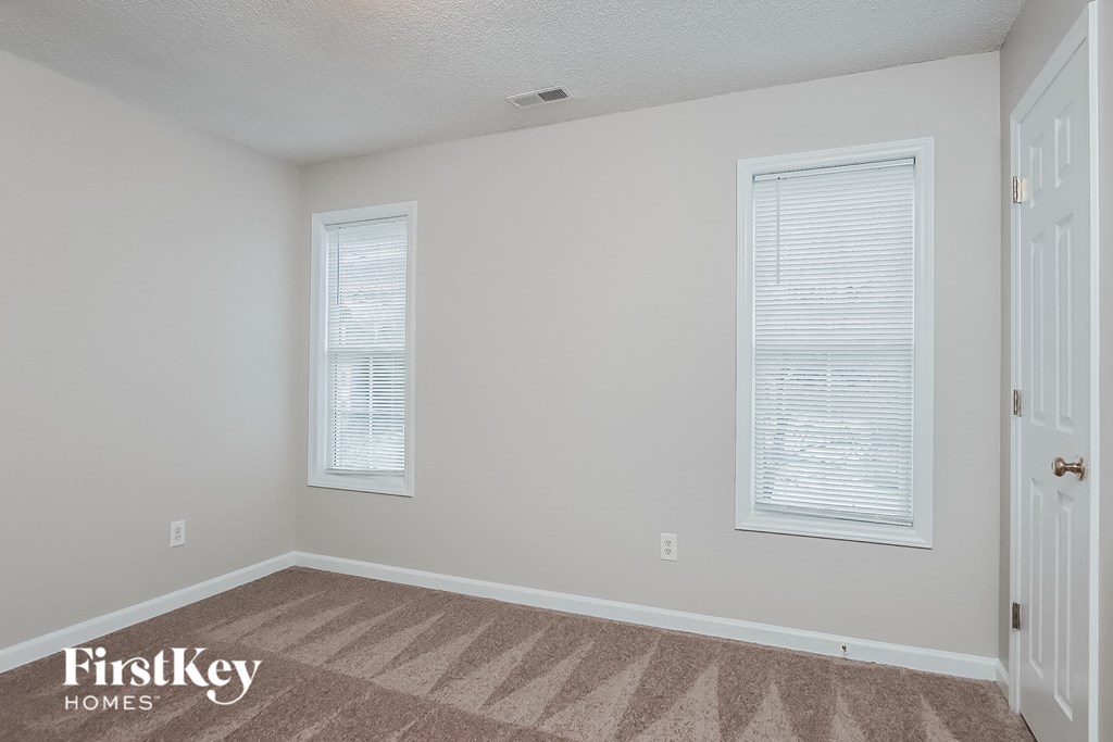 a bedroom with two windows and a carpeted floor