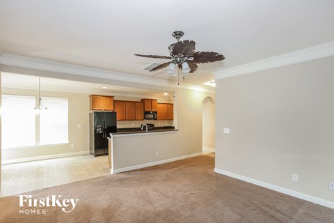 A spacious kitchen and living room with a ceiling fan.