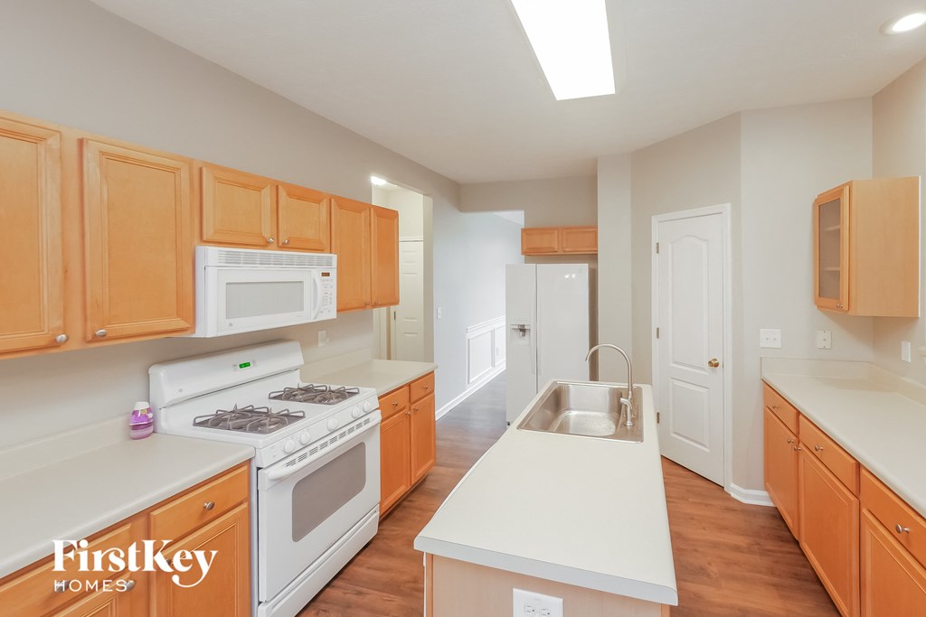 A kitchen with wooden cabinets and a white stove top oven.