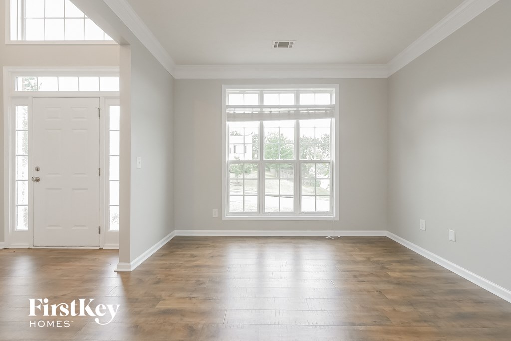 A room with a white door and a window with a view of trees.