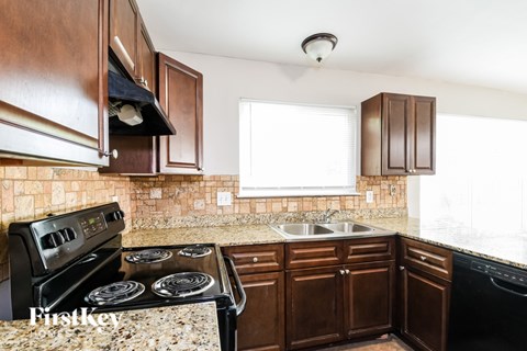 A kitchen with brown cabinets and a black stove top oven.
