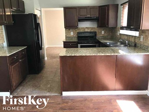 A kitchen with a black fridge and brown cabinets.
