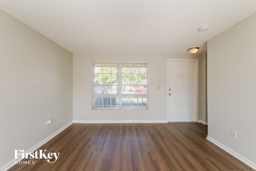 A room with wooden floors and a window overlooking a street.
