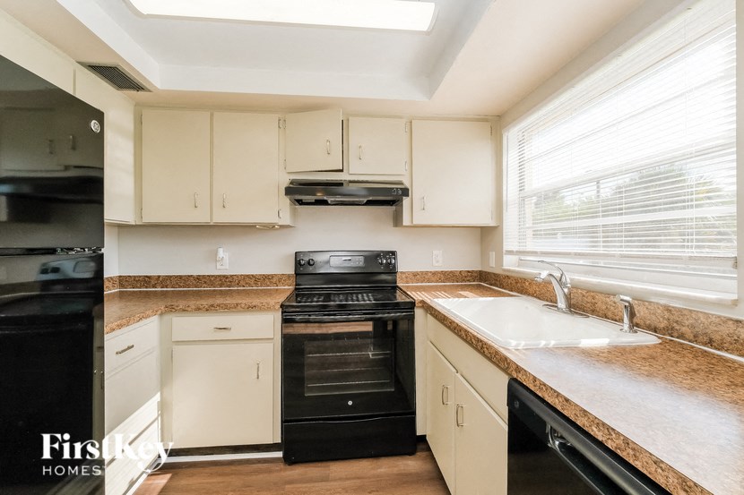 A kitchen with black appliances and white cabinets.