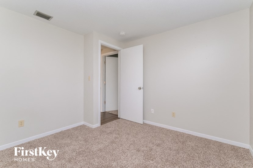 A room with a carpeted floor and a doorway leading to another room.