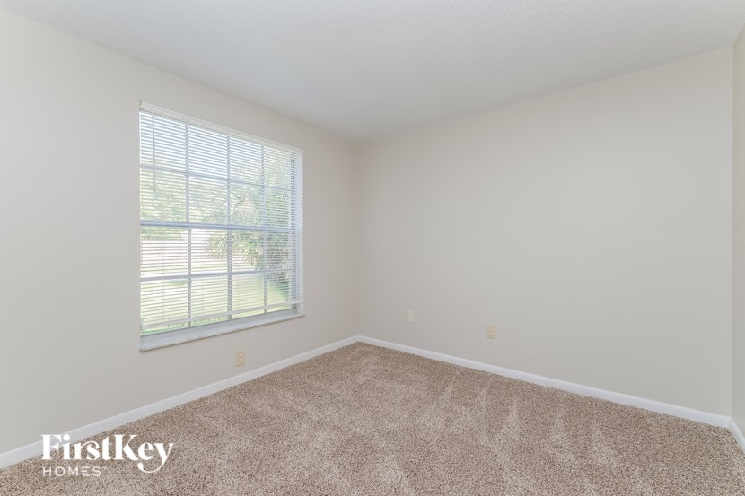 A room with a carpeted floor and a window with blinds.