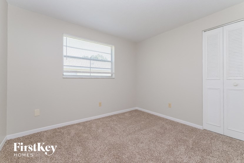 A room with a window and a carpeted floor.