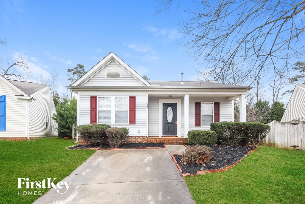 A white house with red shutters and a black door is for sale.