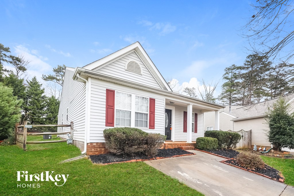 A white house with red shutters and a red door is for sale by FirstKey Homes.