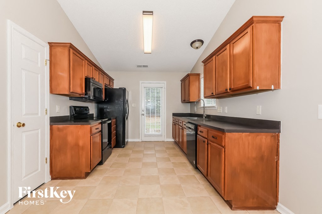 A kitchen with wooden cabinets and black countertops.