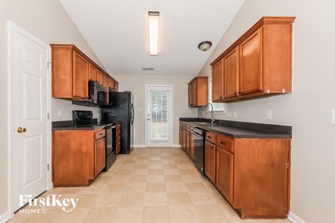 A kitchen with wooden cabinets and black countertops.