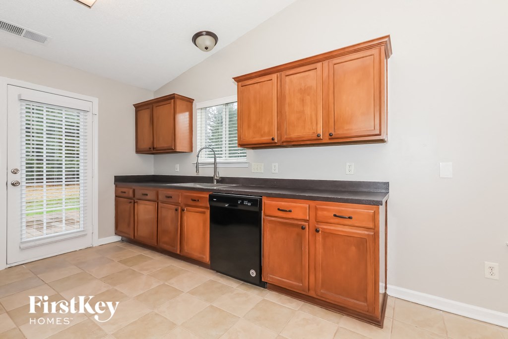 A kitchen with wooden cabinets and black countertops.