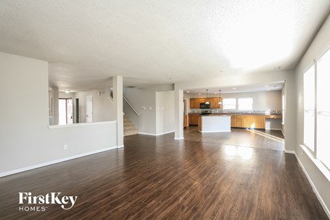 A spacious living room with wood flooring and a staircase leading to another room.