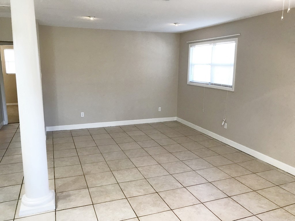 A room with a window and tiled flooring.