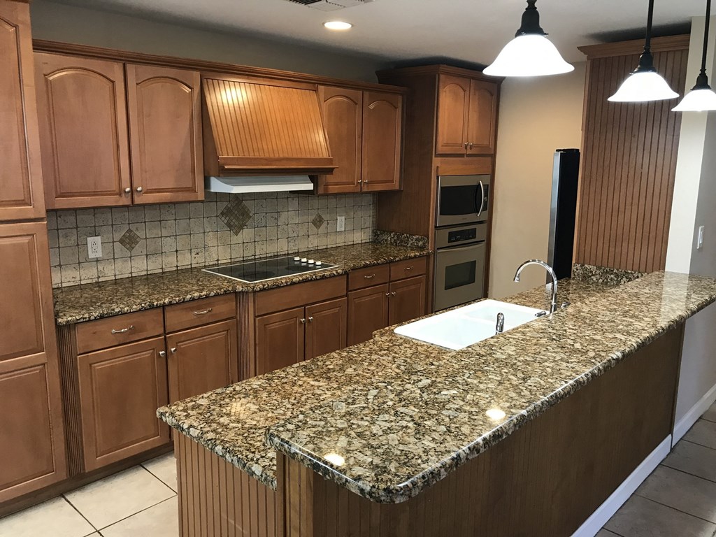 A kitchen with granite countertops and wooden cabinets.