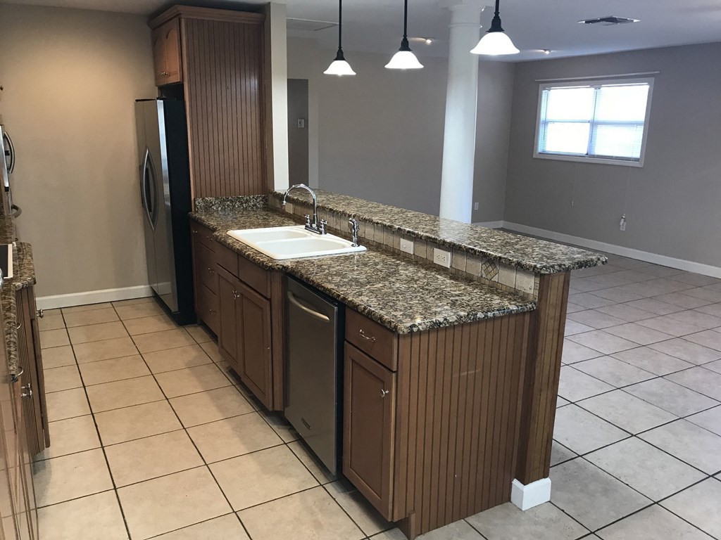 A kitchen with granite countertops and wooden cabinets.